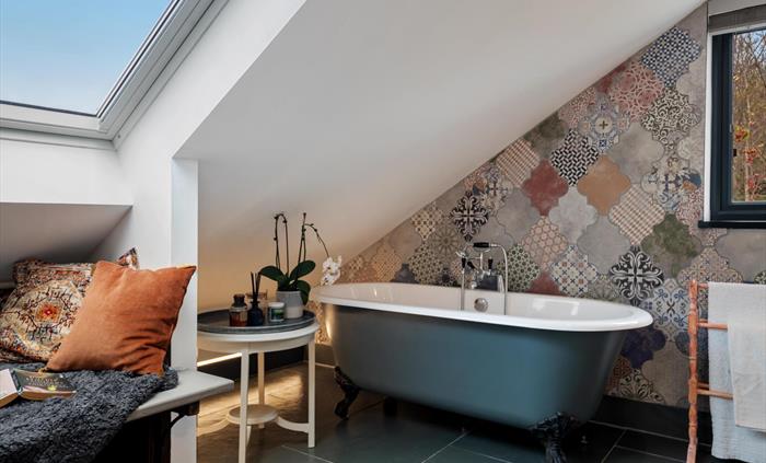 rolltop bath with hand shower, LED mood lighting, homemade lavender bath bombs, seating under Velux windows